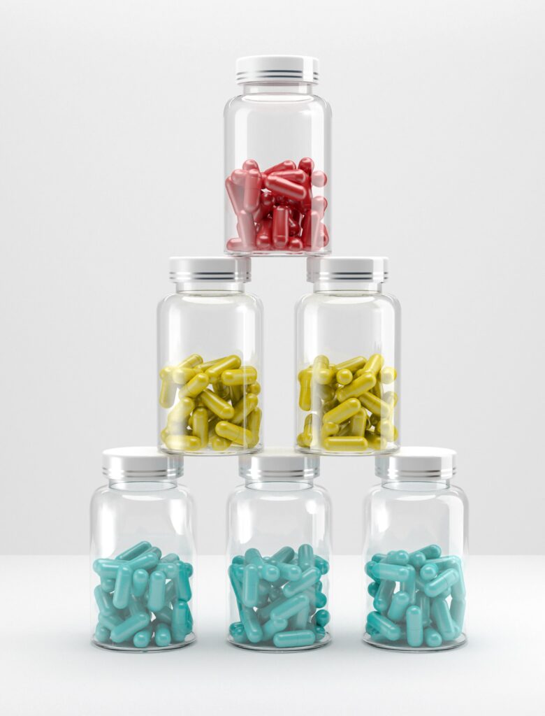 Stack of glass medicine cans with colorful pills on white background. 3D illustration